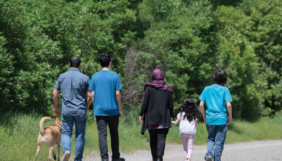 Iranian family of believers walking down a road together with a dog