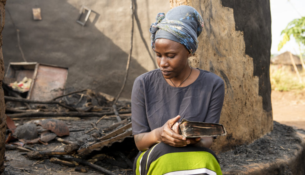 Woman sitting by her burned home. President's Letter Story.