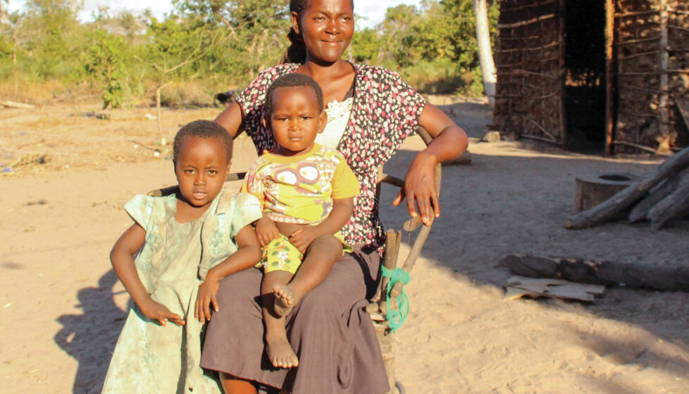 Mother and two children sitting in front of their hut